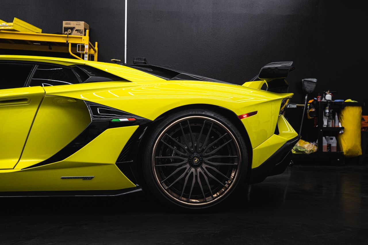 services-03 Close-up of a yellow Lamborghini Aventador parked indoors in a garage setting.